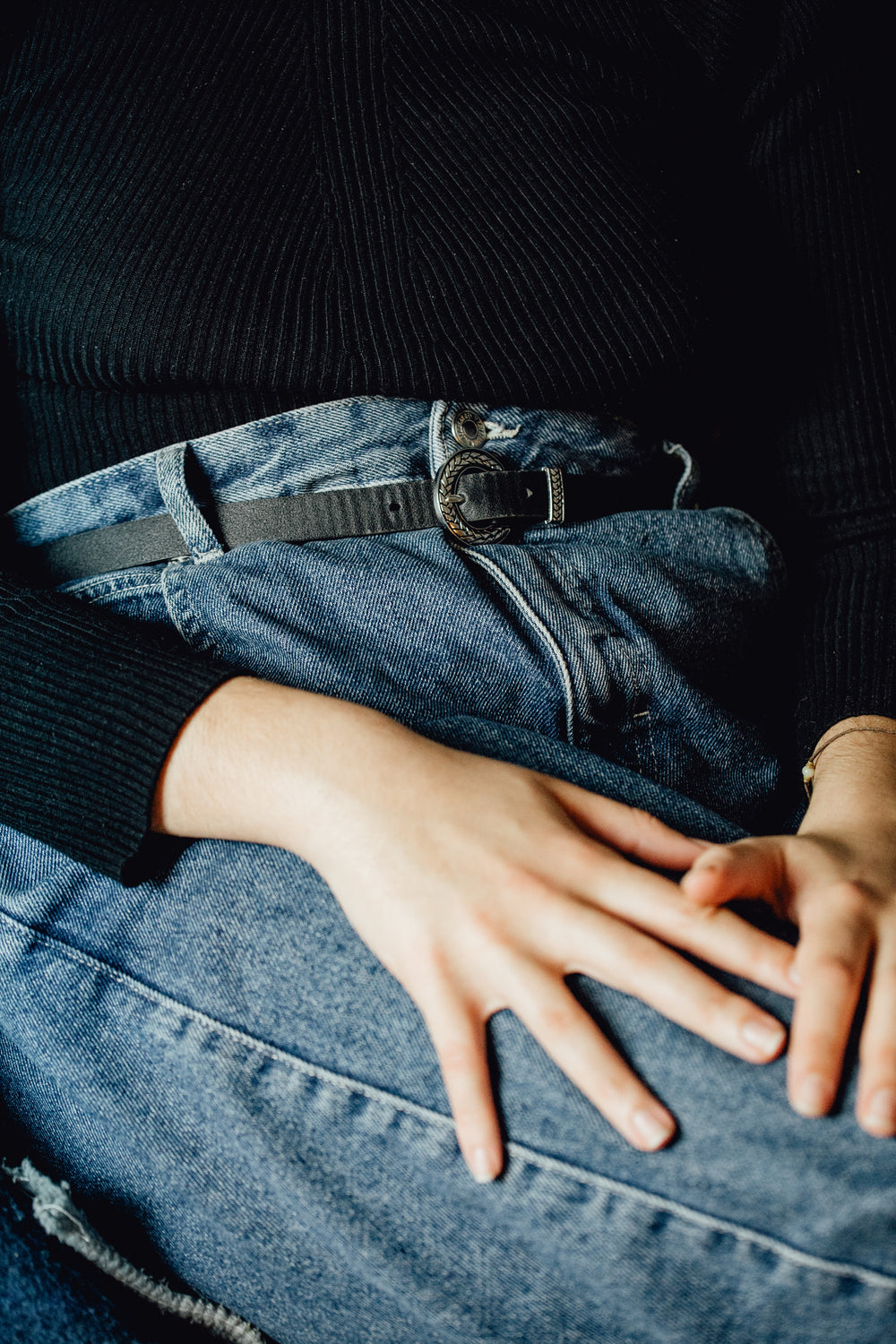 persons in blue jeans lays their hands on their thighs