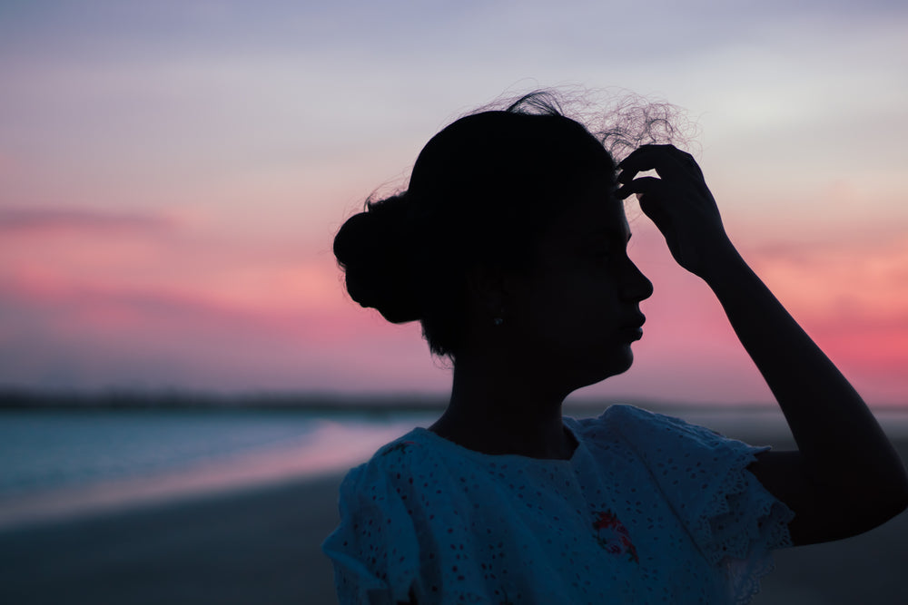 persons silhouetted profile by a beach sunset