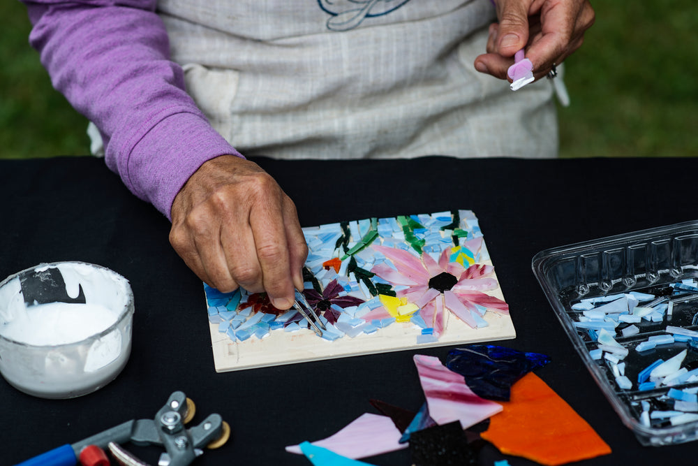 persons uses tweezers to add glass to a mosaic