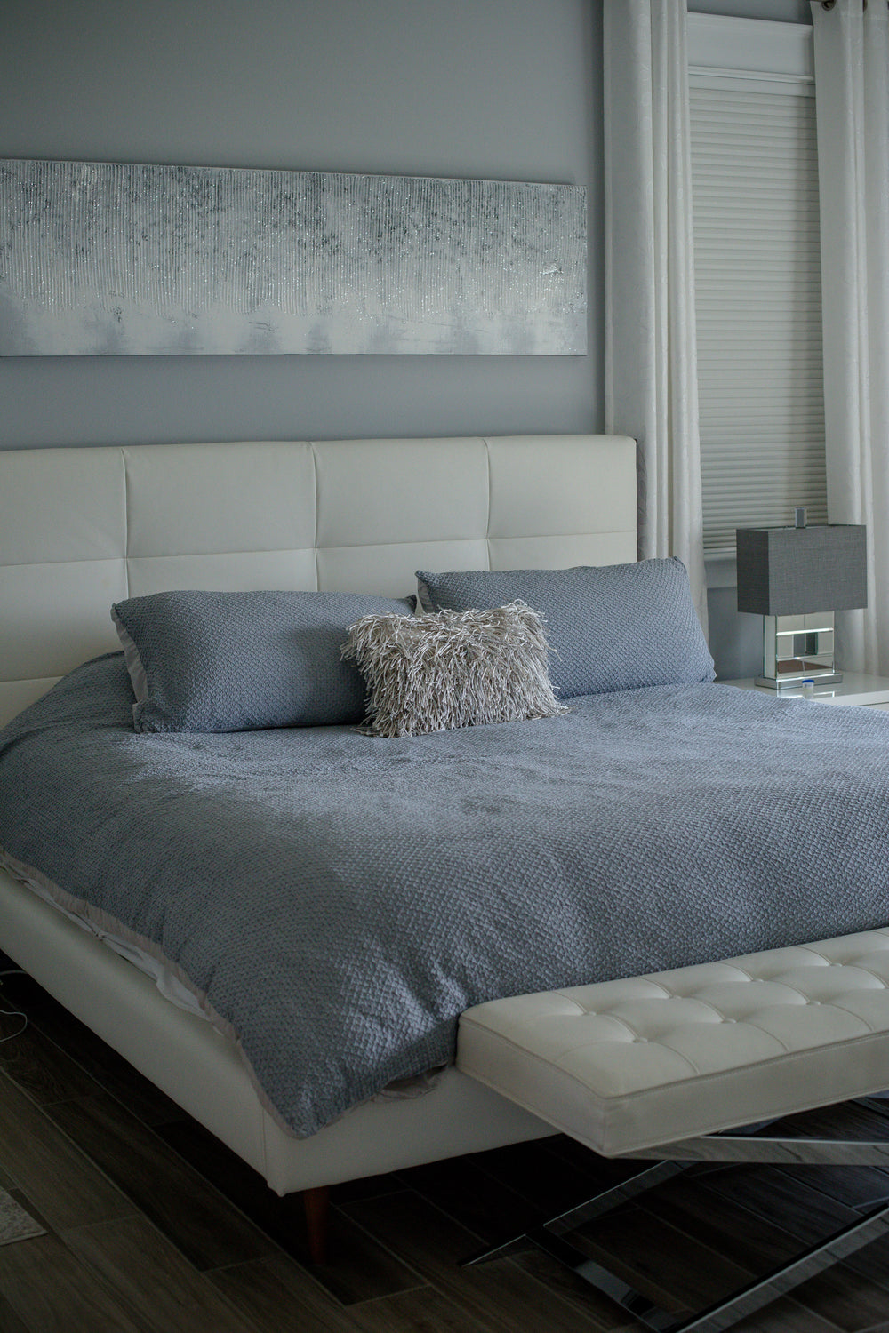 photo of a bed with a white bed frame and blue sheets