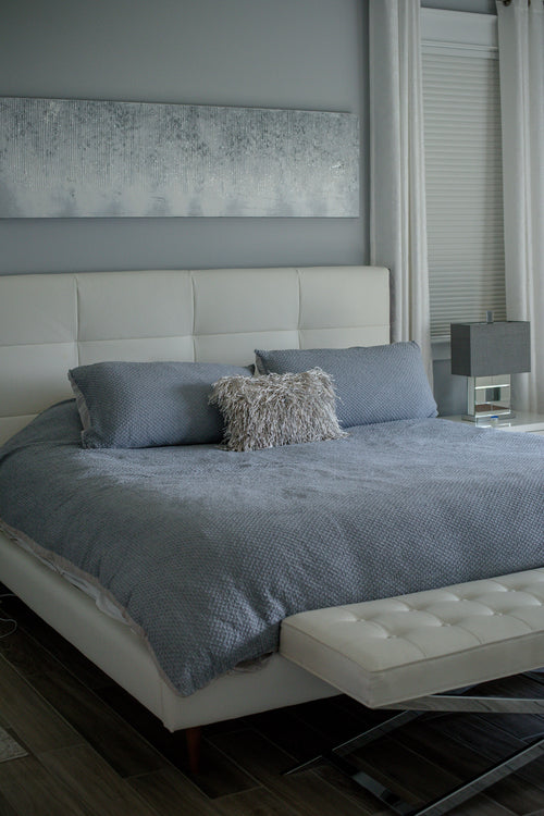 photo of a bed with a white bed frame and blue sheets