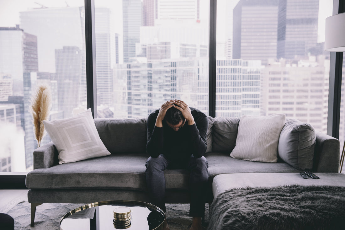 A person sitting quietly on a couch in a softly lit living room