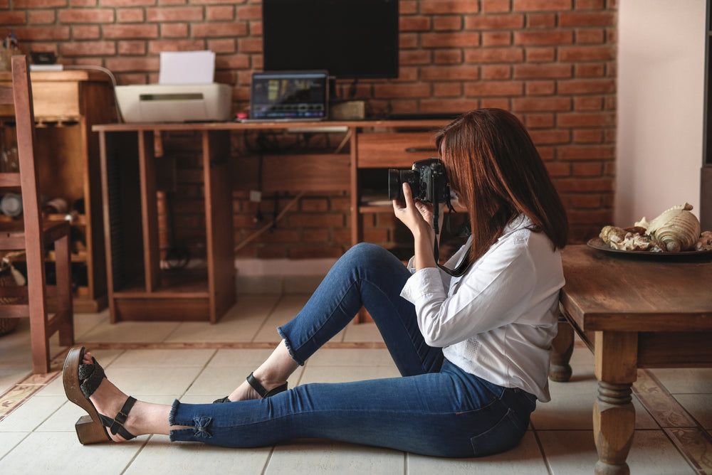 photographer sits on floor holding a camera to their face