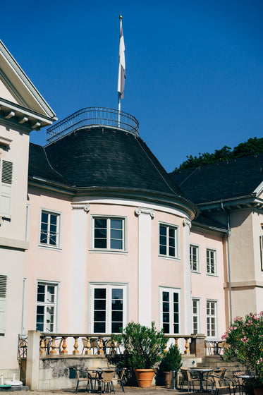 pink building with a black roof and a flag pole