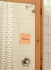 pink note reads breath on a bathroom mirror
