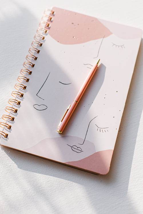 pink notebook and pink pen