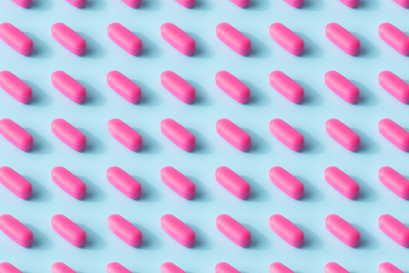 modello di pillola rosa su una superficie azzurro chiaro