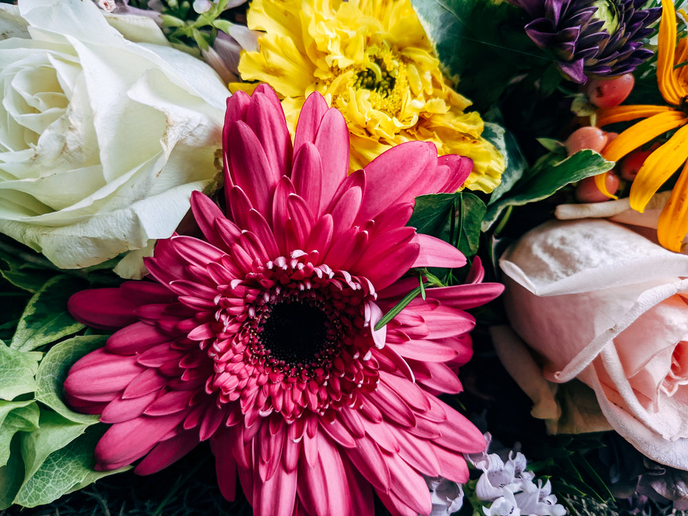 pink yellow and white bouquet surrounded by roses