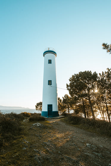 portrait blue and white lighthouse at sunset