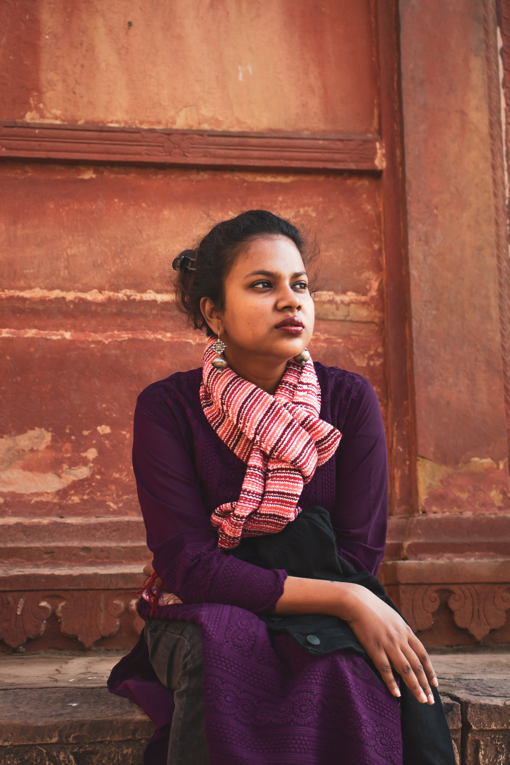 portrait of a person sat near a rust colored wall