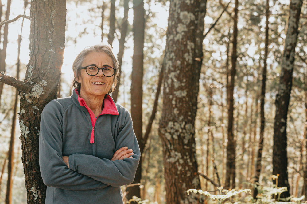 portrait of a woman smiling while standing in a forest