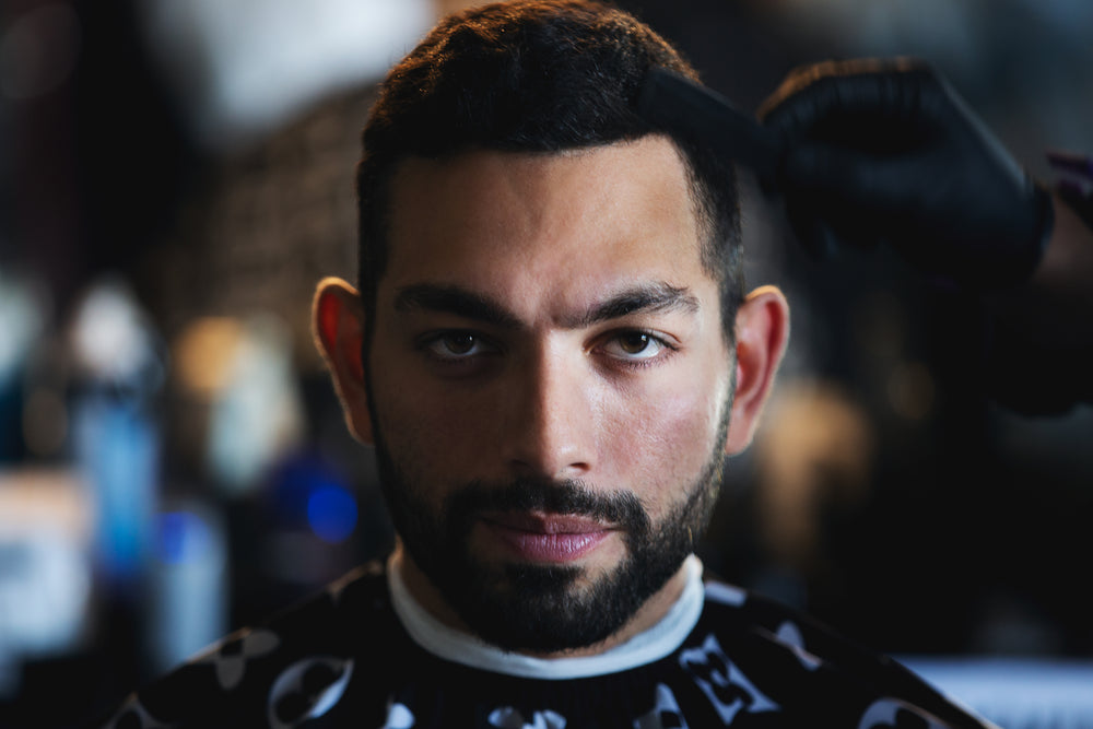 portrait of man as the barber adds final touches