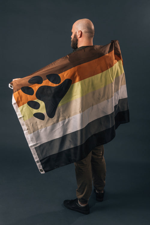 portrait of man holding bear pride flag