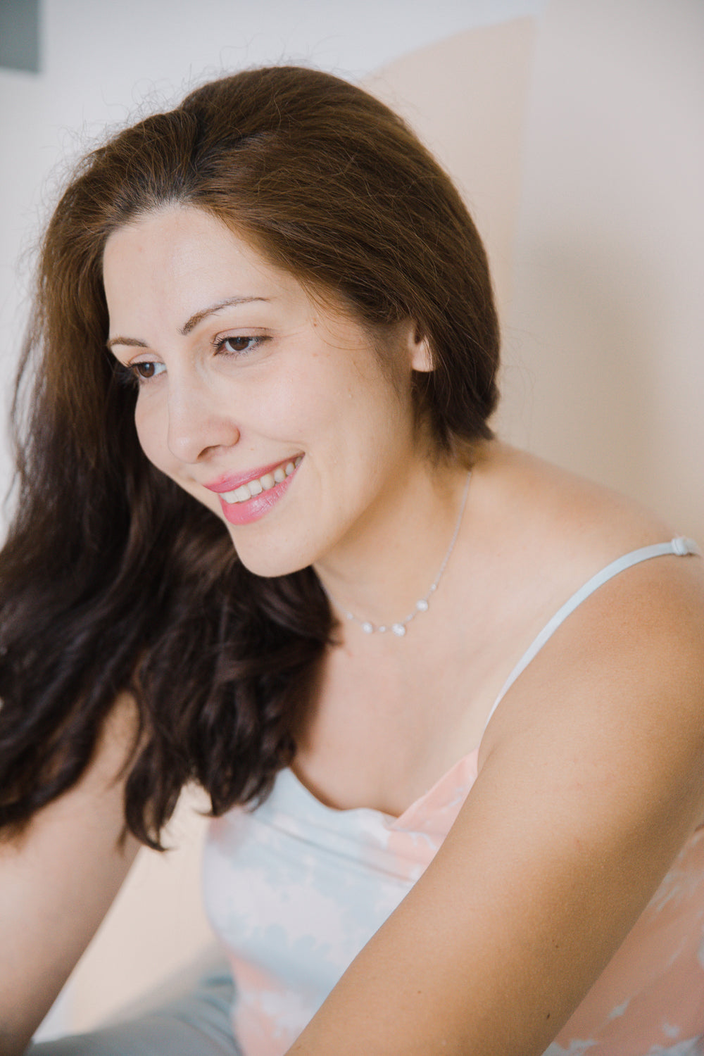 portrait of person with long brown hair smiling in white