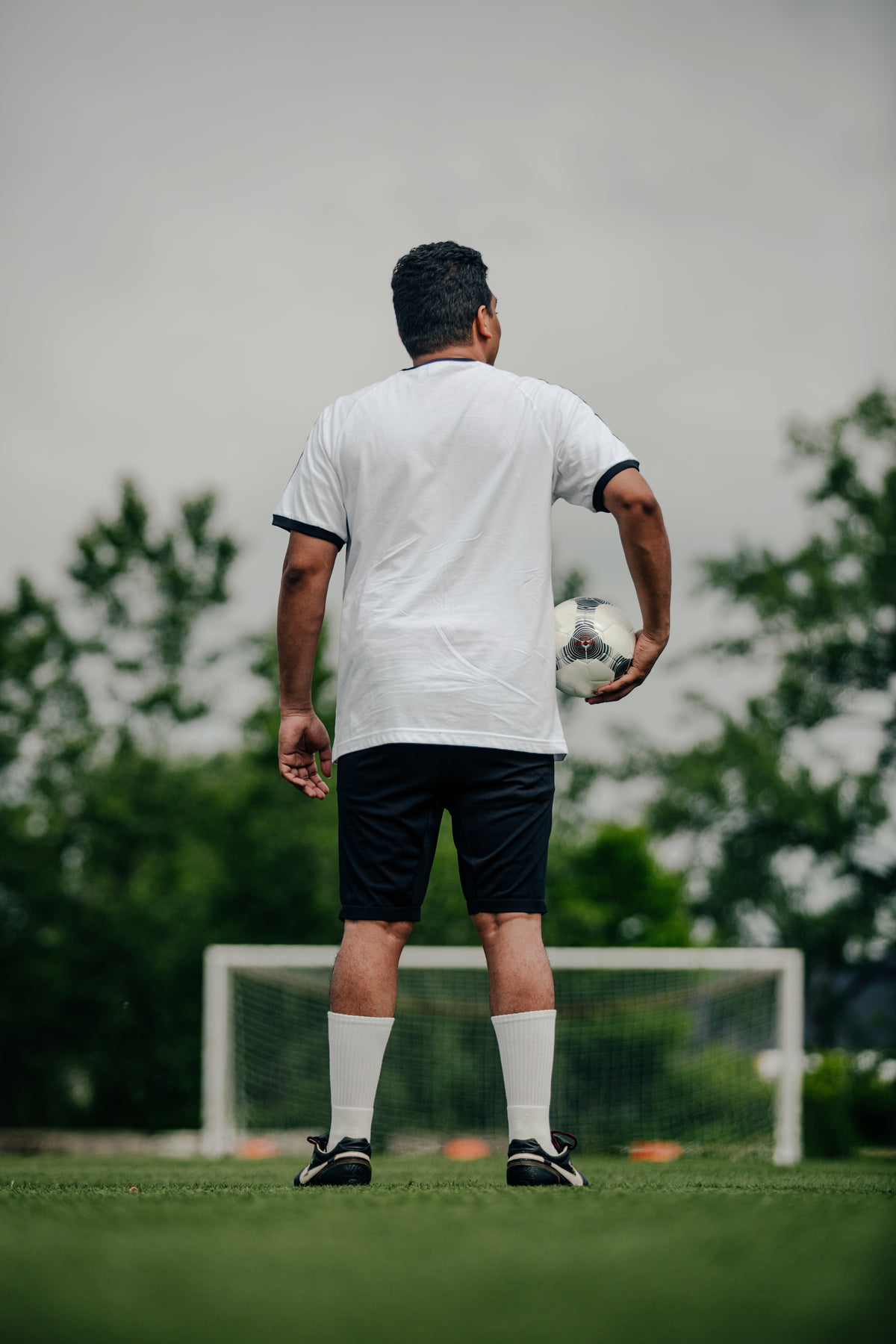 foto de jogador de futebol segurando uma bola em um campo vazio