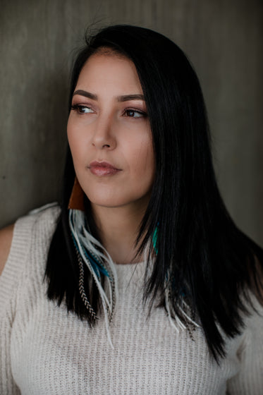 portrait of woman wearing long feather earrings