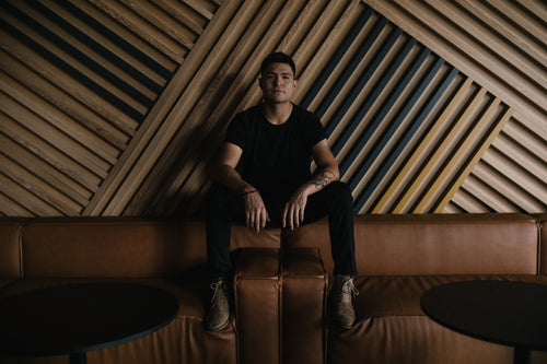 portrait of young man against large geometric wood wall