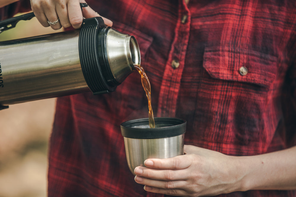 pouring coffee from a thermus in the woods