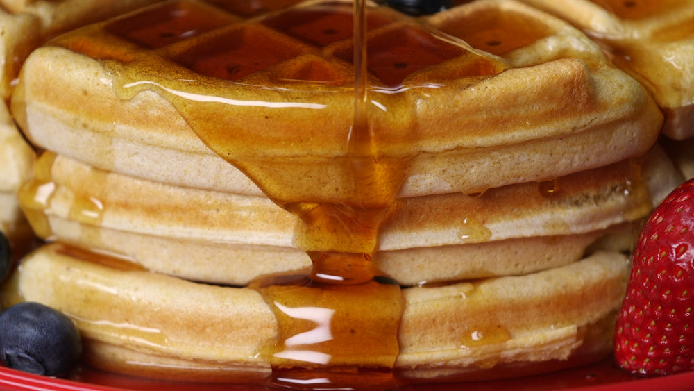 pouring maple syrup on waffles