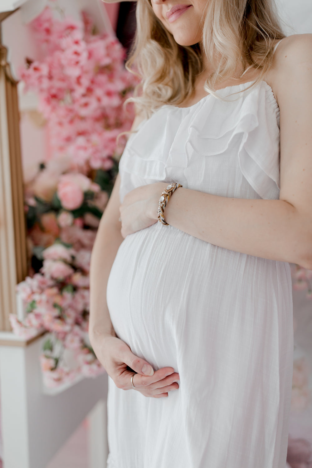 pregnant woman in a white dress holds her belly