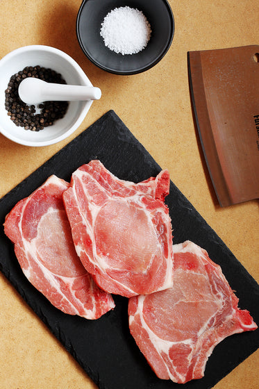 prepping and seasoning raw pork chops with slate and cleaver