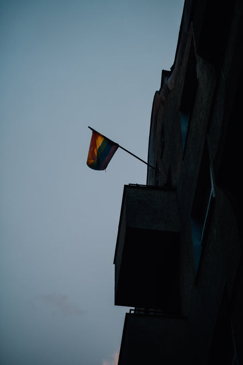 pride flag hangs on a building at sunset