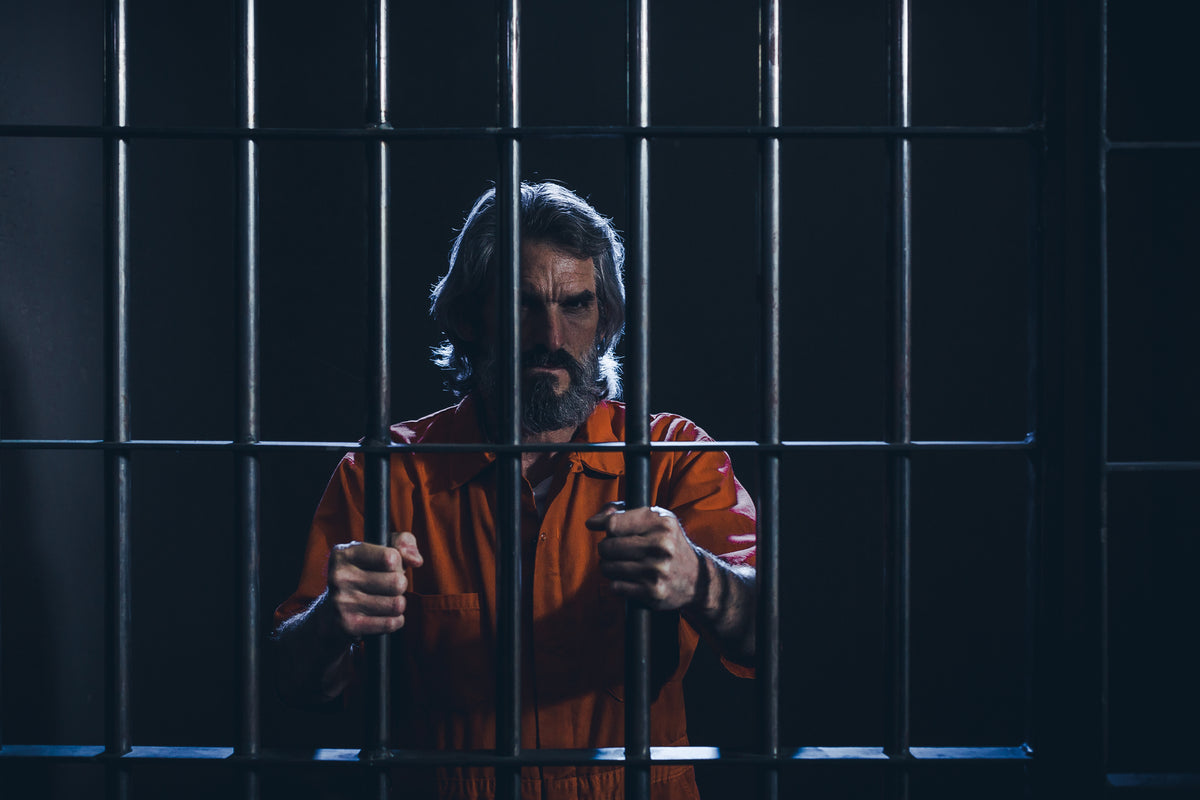 prisoner holds cell bars tightly