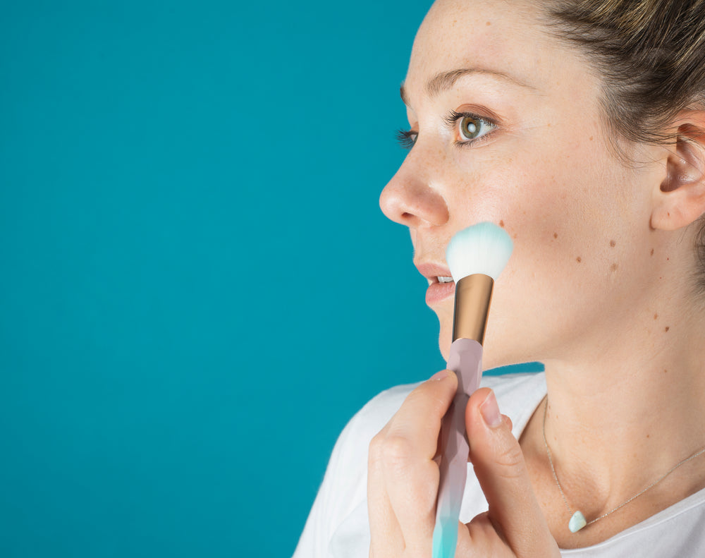 profile of a person adding blush to her cheeks with a brush