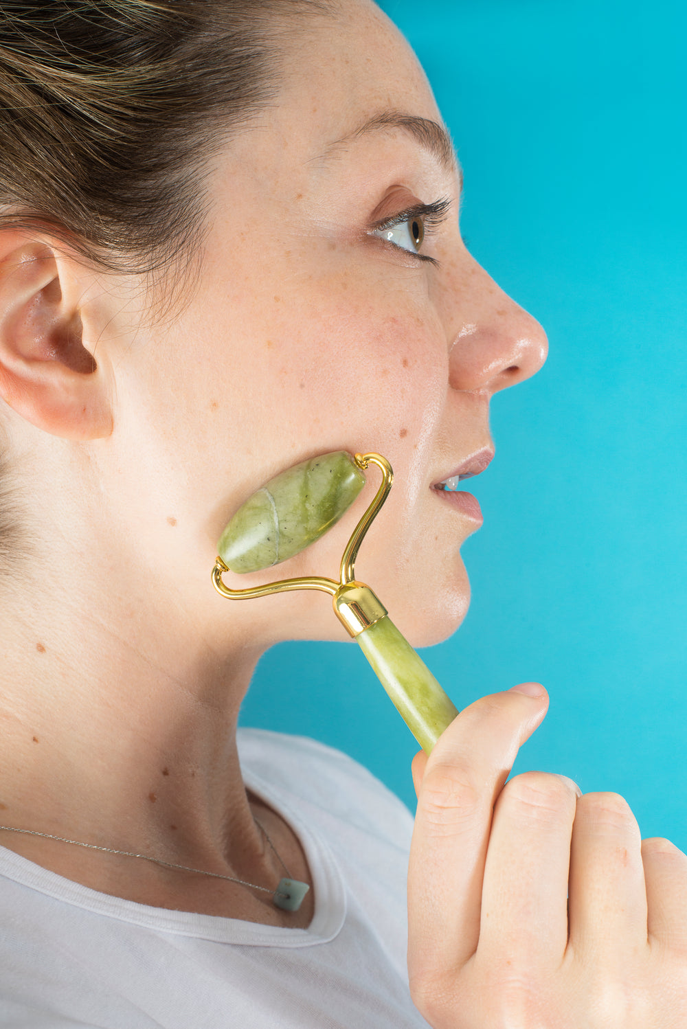 profile of a woman using a jade face roller