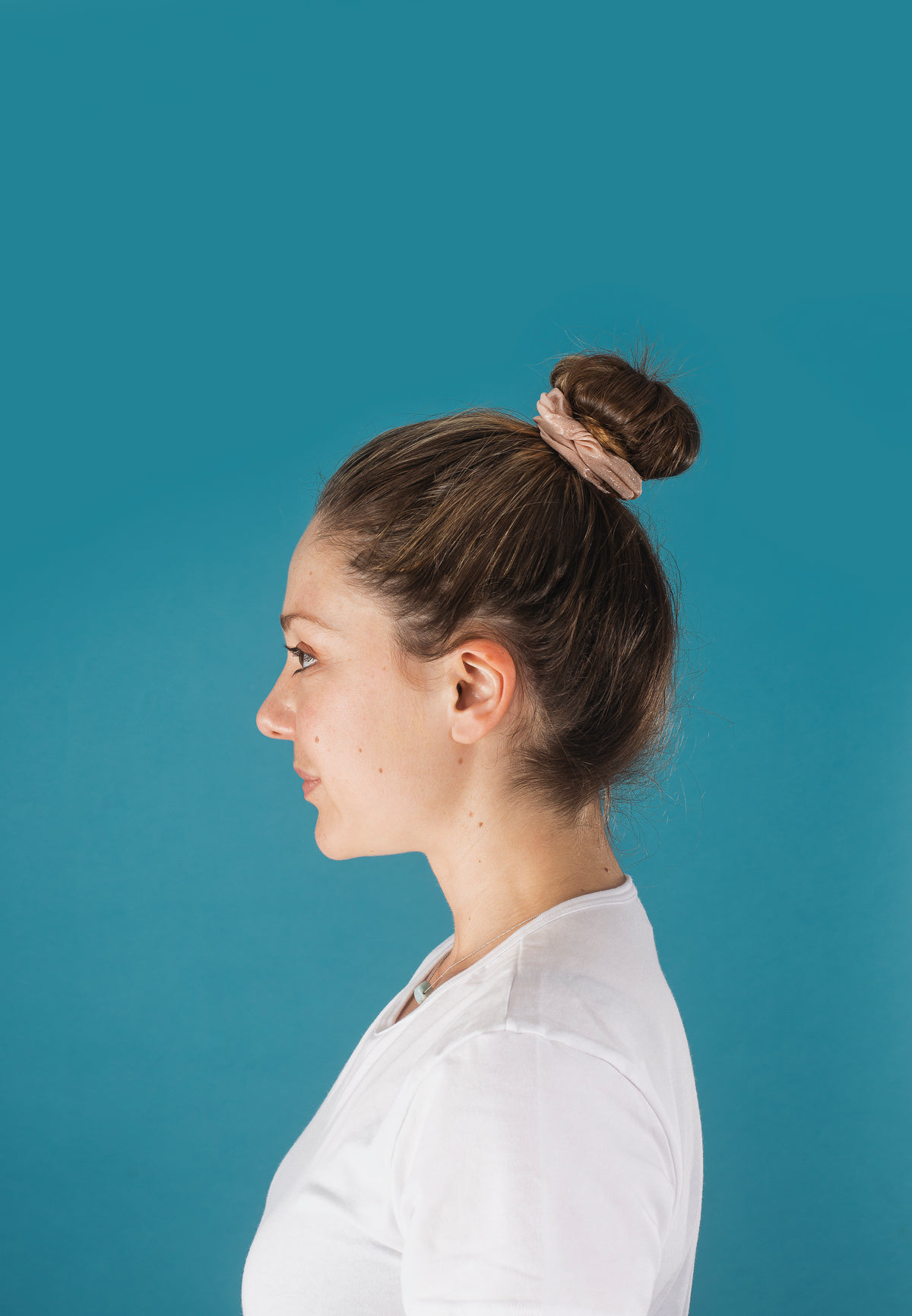 profile of a woman with her hair in a scrunchie bun