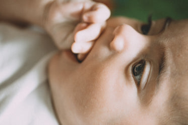 profile of baby holding their hand in mouth