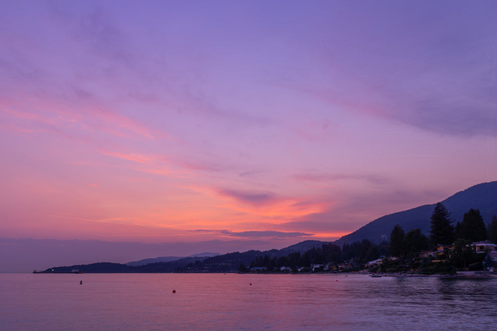 purple sunset reflects off calm coastal waters