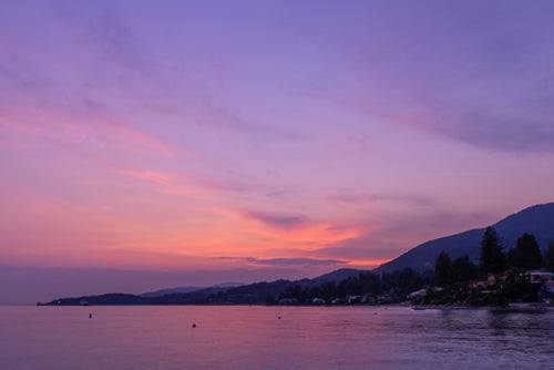 purple sunset reflects off calm coastal waters