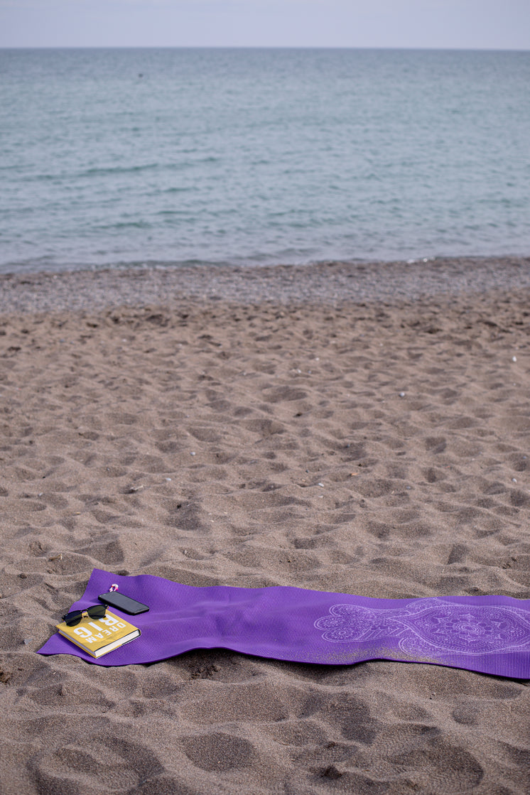 Purple Towel On A Beach With Book And Cellphone
