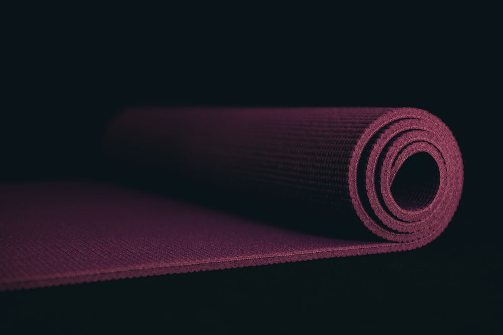 purple yoga mat on a black floor