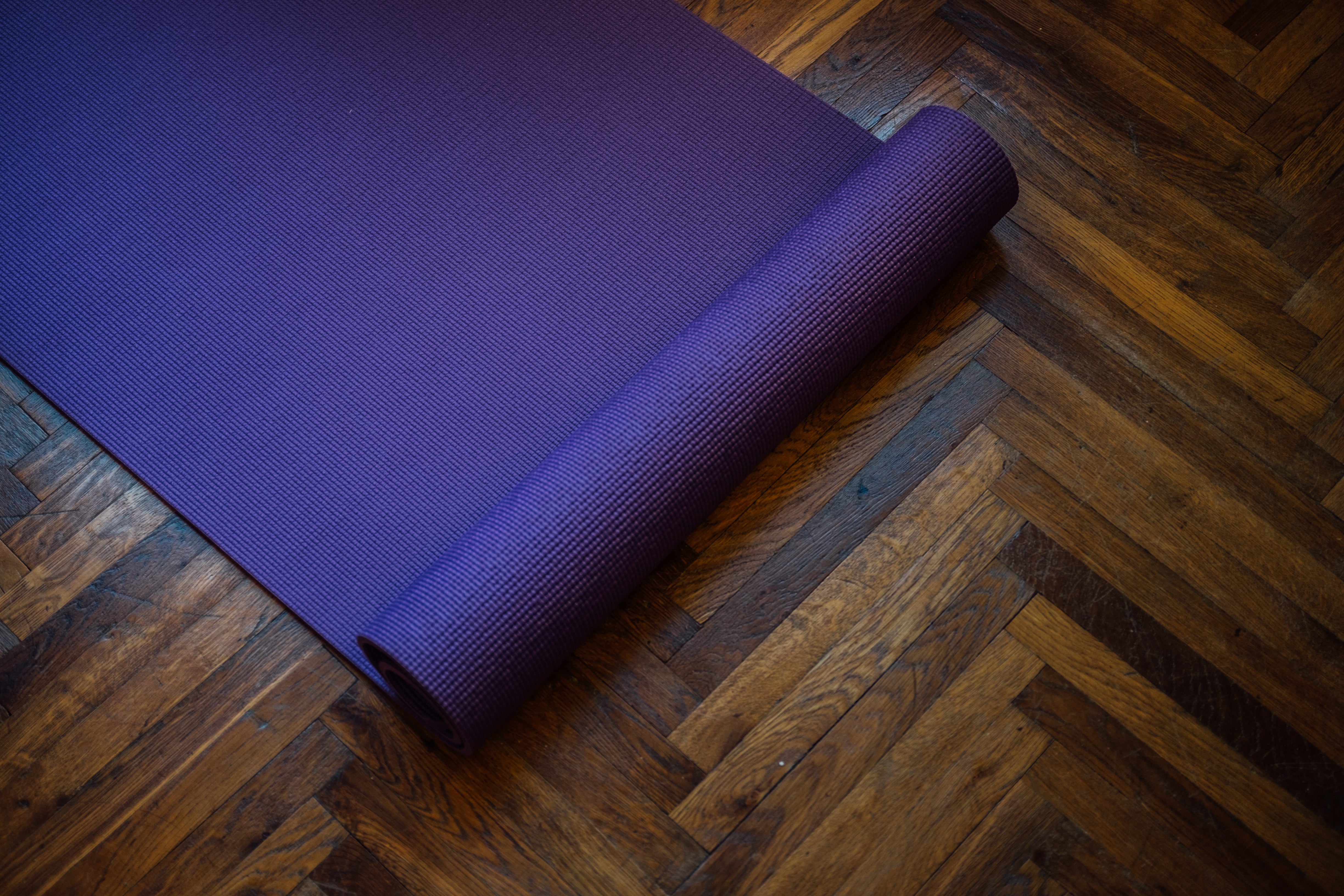 Browse Free HD Images of Purple Yoga Mat Partially Rolled On A Wooden Floor