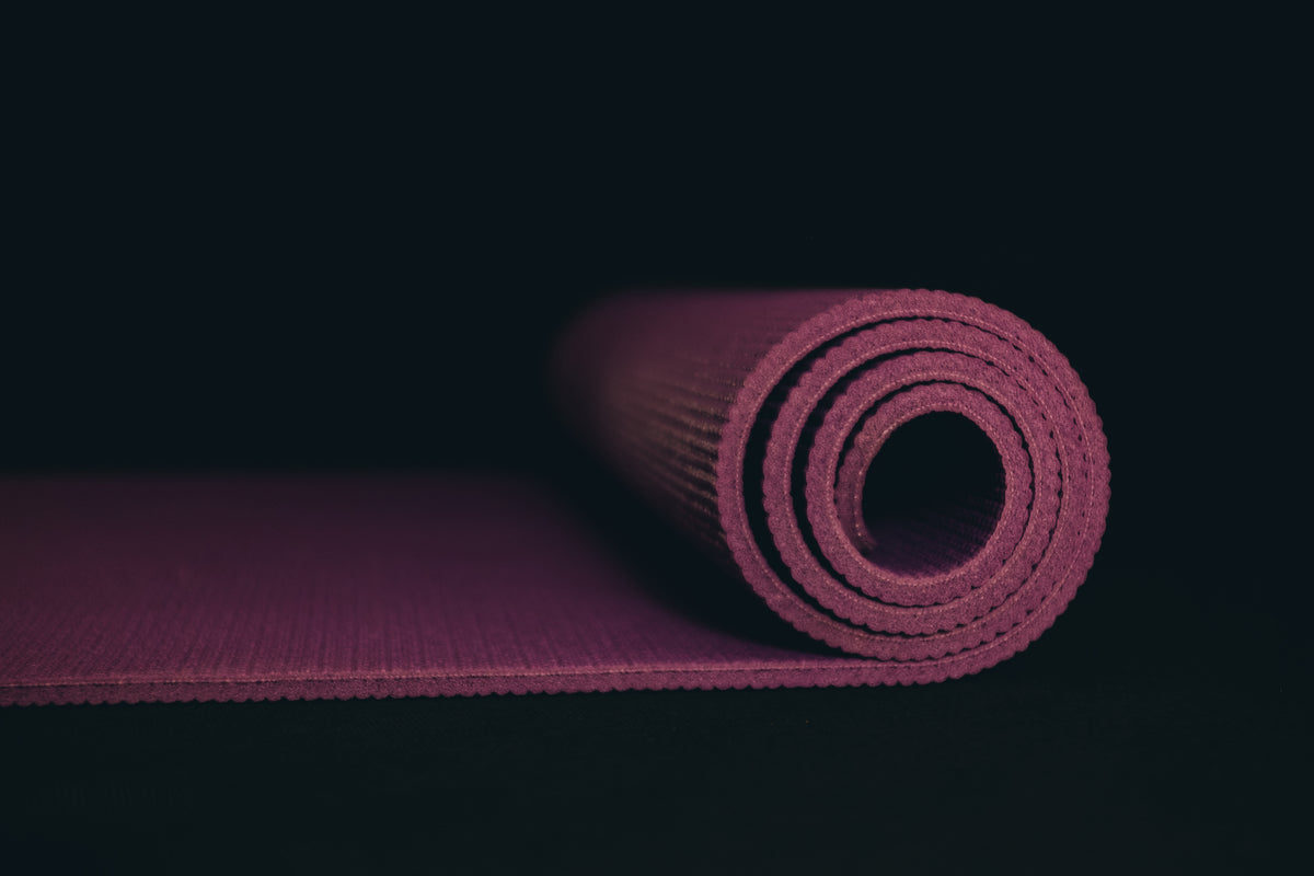 purple yoga mat partially rolled on black