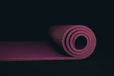 purple yoga mat partially rolled on black