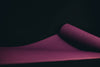 purple yoga mat unrolled on a black floor