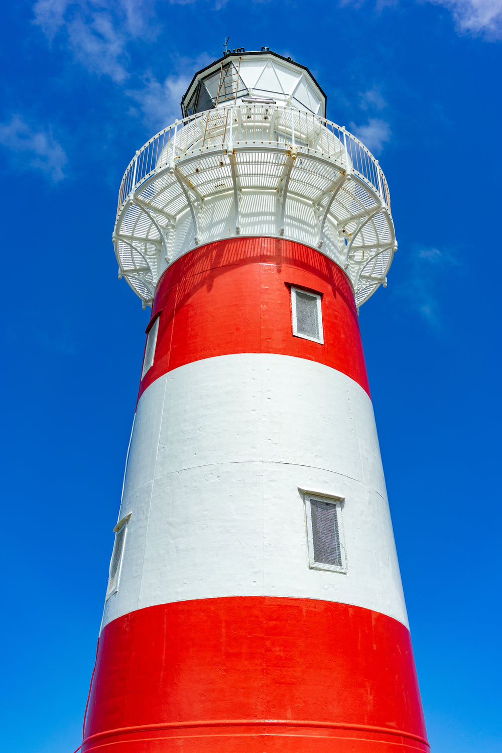 rad and white lighthouse on blue sky