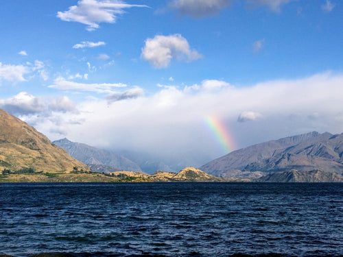 rainbow reaches for clouds by shore