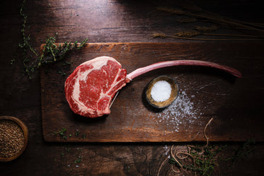 raw red meat lays in a wooden cutting board