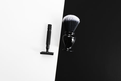razor and shaving brush on black and white
