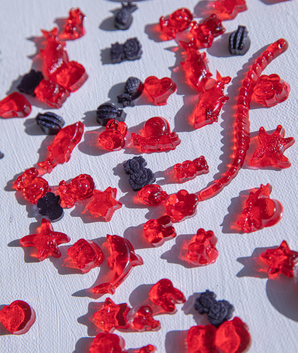 red and black gummies on white surface