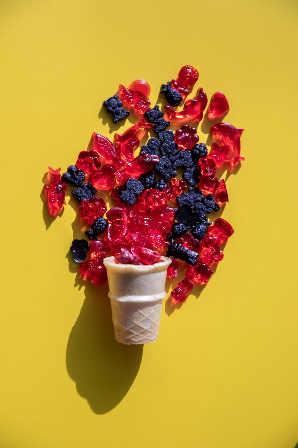 red and black gummies spill out of an icecream cone