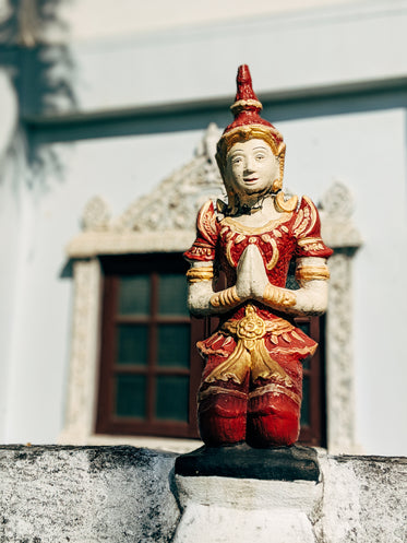 red and gold statue of a person praying
