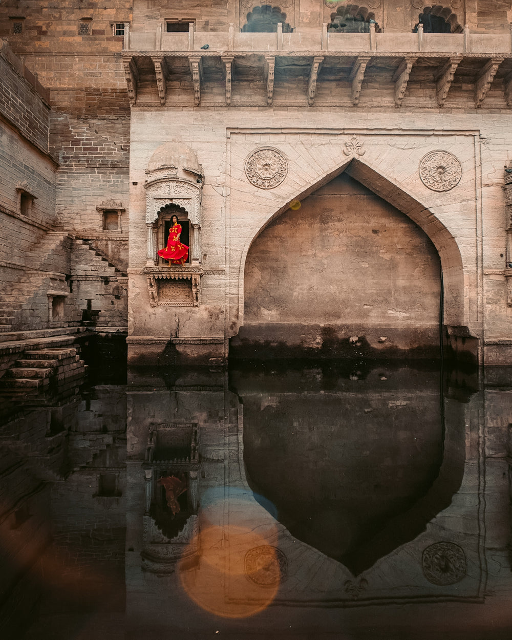 red dressed woman poses in front of intricate monument