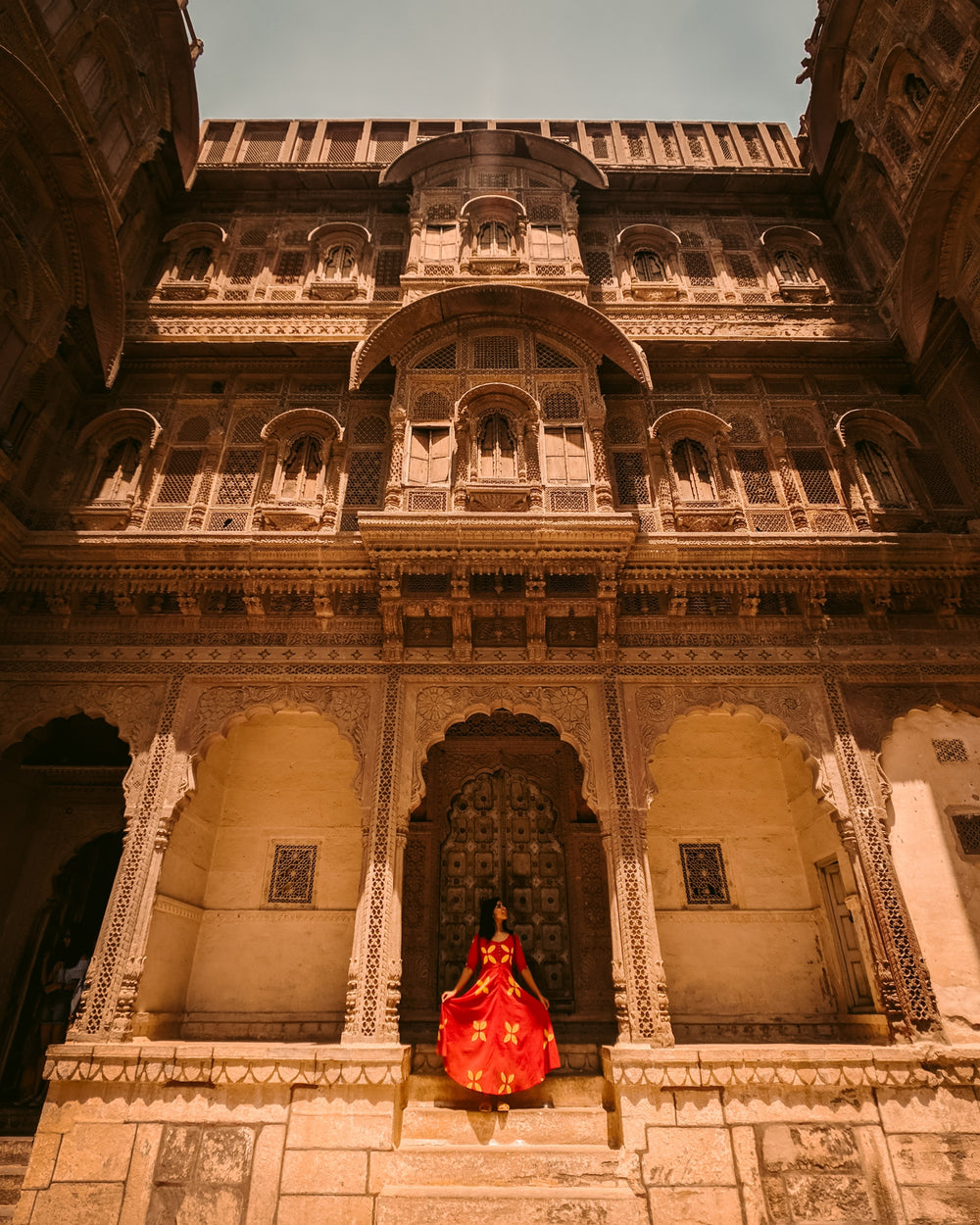 red dressed woman poses in front of temple