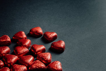 red foiled chocolate hearts scattered on black
