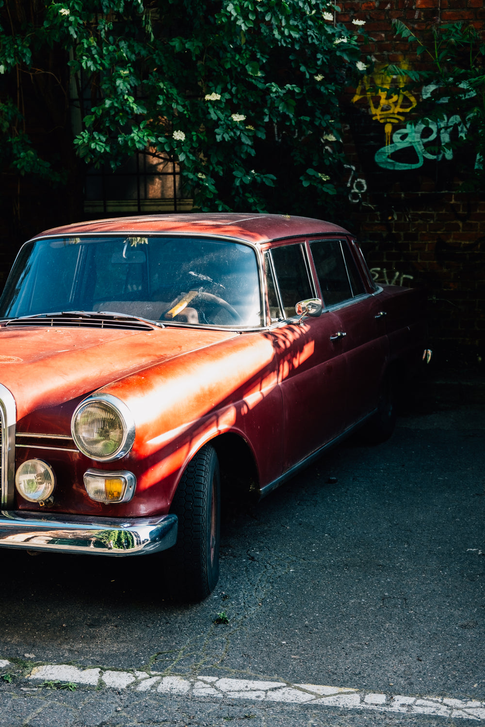 red vintage car parked by brick wall